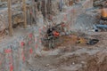 Worker in the foundation trench with construction machinery on the construction site