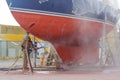 Worker, sandblasting the corrode hull of a sailing vessel