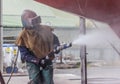 Worker, sandblasting the corrode hull of a sailing vessel