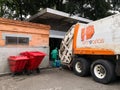 Worker garbage collector and a trash truck parked in industrial dumpster