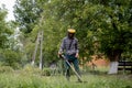 Worker with a gas mower in his hands, mowing grass in front of the house. Trimmer in the hands of a man. Gardener cutting the Royalty Free Stock Photo