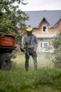 Worker with a gas mower in his hands, mowing grass in front of the house. Trimmer in the hands of a man. Gardener Royalty Free Stock Photo