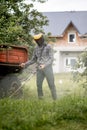 Worker with a gas mower in his hands, mowing grass in front of the house. Trimmer in the hands of a man. Gardener cutting the Royalty Free Stock Photo