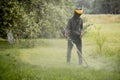 Worker with a gas mower in his hands, mowing grass in front of the house. Trimmer in the hands of a man. Gardener cutting the Royalty Free Stock Photo