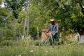 Worker with a gas mower in his hands, mowing grass in front of the house. Trimmer in the hands of a man. Gardener cutting the Royalty Free Stock Photo