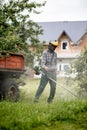 Worker with a gas mower in his hands, mowing grass in front of the house. Trimmer in the hands of a man. Gardener cutting the Royalty Free Stock Photo