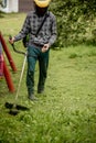 Worker with a gas mower in his hands, mowing grass in front of the house. Trimmer in the hands of a man. Gardener cutting the Royalty Free Stock Photo