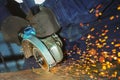 Worker in gloves and overalls angle grinder cuts a metal sheet. Industrial background of the labor process Royalty Free Stock Photo