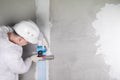 A worker glues the seams with a special mesh tape on a concrete wall using a spatula, there is a place for your inscription