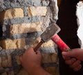 worker with a hammer and chisel makes a hole in the wall at the construction site Royalty Free Stock Photo