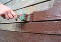 Worker hand with brush painting and repair wooden wall. Paint Old Wooden Surface. Royalty Free Stock Photo