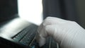 Worker hand with glove working with a computer typing on a laptop Royalty Free Stock Photo