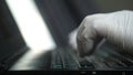 Worker hand with glove working with a computer typing on a laptop Royalty Free Stock Photo