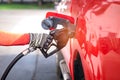 Worker hand holding nozzle for filling diesel fuel into red car at refuel station Royalty Free Stock Photo