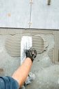 Worker hand plastering, adding adhesive with comb trowel