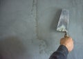 Worker hand plastering and smoothing concrete wall with cement and a steel trowel, on construction site Royalty Free Stock Photo