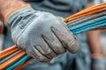 Worker hand in protective glove holding a bundle of colorful electrical cables Royalty Free Stock Photo