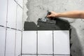 The worker hand is putting tiles adhesive to the wall with the notched trowel Royalty Free Stock Photo