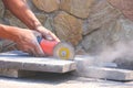 Worker hand using grinder cutting stone tile floor for paving pavement job, close up shot with copy space Royalty Free Stock Photo