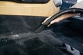 Worker hand with vacuum cleaner cleans car trim