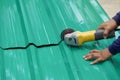 Worker hands cutting a metal sheet for roofing by using an angle grinder on the floor Royalty Free Stock Photo