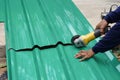 A worker hands cutting a metal sheet for roofing by using an angle grinder on the floor Royalty Free Stock Photo