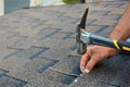Worker hands installing bitumen roof shingles. Worker Hammer in Nails on the Roof. Roofer is hammering a Nail in the Roof Shingles Royalty Free Stock Photo