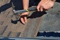 Worker hands installing bitumen roof shingles. Worker Hammer in Nails on the Roof. Roofer is hammering a Nail in the Roof Shingles