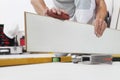 Worker hands installing timber laminate white floor. Precise finishing using sandpaper. Wooden floors house renovation