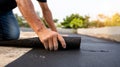 Worker hands unrolling black waterproofing membrane on flat rooftop outdoors. Professional roofer installing protective felt Royalty Free Stock Photo