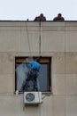 Worker hanging repair broken glass on window, two colleagues help him