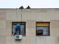 Worker hanging repair broken glass on window, two colleagues help him