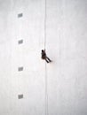 Worker hanging from rope on building wall