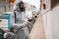 Worker in hazmat suit wearing gas mask protection while making disinfection in city street - Coronavirus decontamination for
