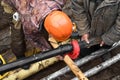 Worker in helmet repairs communal water pipe in trench on street. Work of public utilities to eliminate accident