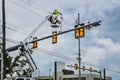 Worker high up in crane basket repairing traffice lights at intersection with building in background