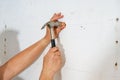 A worker is hitting a screw on the wall with a hammer Royalty Free Stock Photo