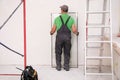 Worker holding double glazing indoors, back view. Window installation Royalty Free Stock Photo