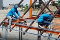 Worker holding electric drill working and installing structure of Galvanized steel pipe, roof steel on roof structure on construct