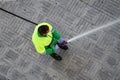 Worker holding a hose cleaning the sidewalk with water