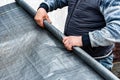 Worker holding roll of vapor barrier membrane for floor and roof.