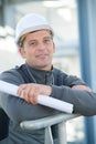 Worker holding rolled blueprint posing and smiling Royalty Free Stock Photo