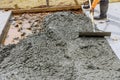 Worker is holding a steel trowel smoothing leveling over freshly poured concrete sidewalk in construction area Royalty Free Stock Photo