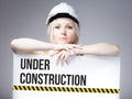 Worker holding under construction sign on information board