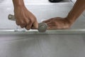 Worker holding a wheel tool to install a aluminum mosquito net wire mesh screen this is to be attached to the window of th Royalty Free Stock Photo