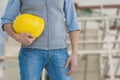 Worker holding a yellow helmet against construction Royalty Free Stock Photo