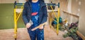 Worker holds a palette-knife for flattening the ceiling from wooden platform in room of apartment is inder construction Royalty Free Stock Photo