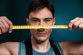 A worker holds a tape measure in front of his face