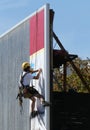 A worker hung on a rope changes an advertisement on a billboard