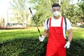 Worker with insecticide sprayer near green bush. Pest control Royalty Free Stock Photo